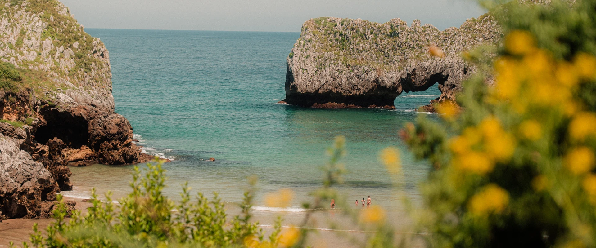Casas con piscina privada en la costa, cala de aguas turquesas con arco de roca