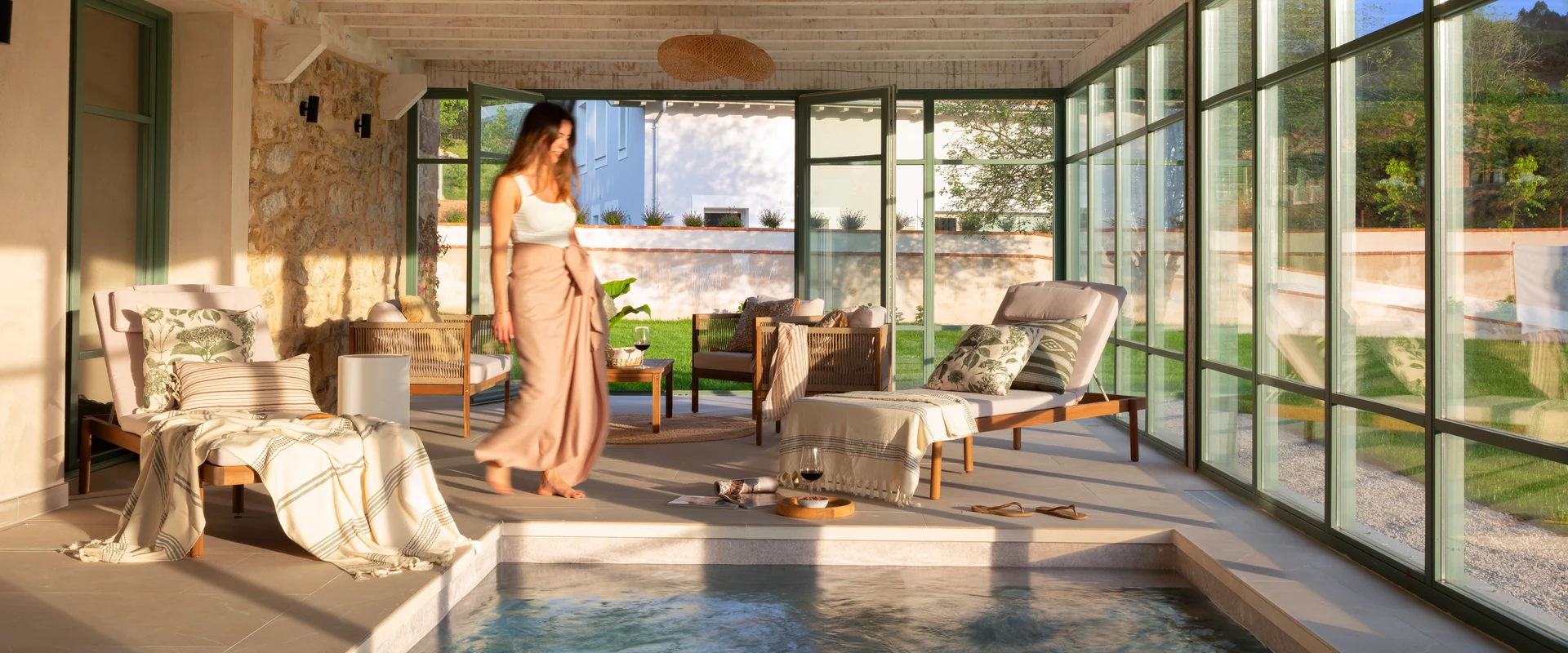 Villa de lujo con piscina privada interior, zona de descanso con tumbonas y ventanales hacia el jardín