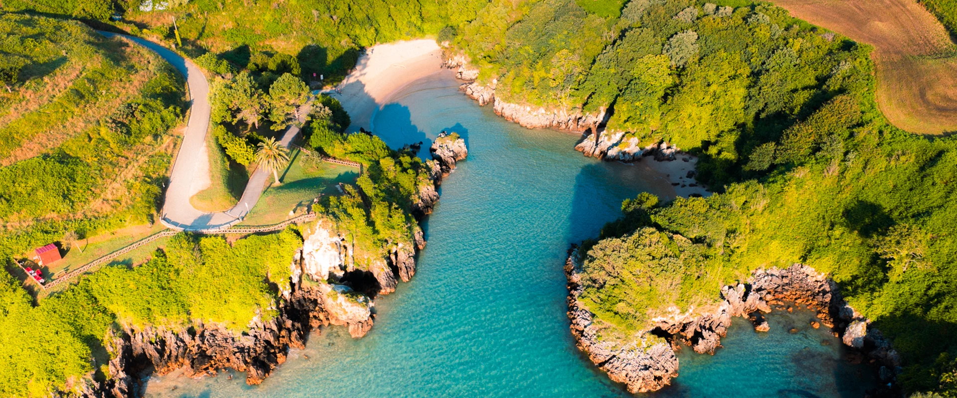 Villas con piscina privada en la costa de Cantabria, vista aérea de una cala de aguas turquesas rodeada de acantilados verdes